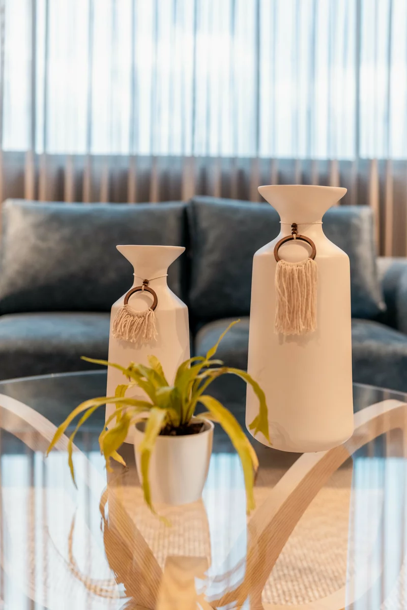 Detalle decorativo: jarrones de cerámica y planta sobre mesa de vidrio