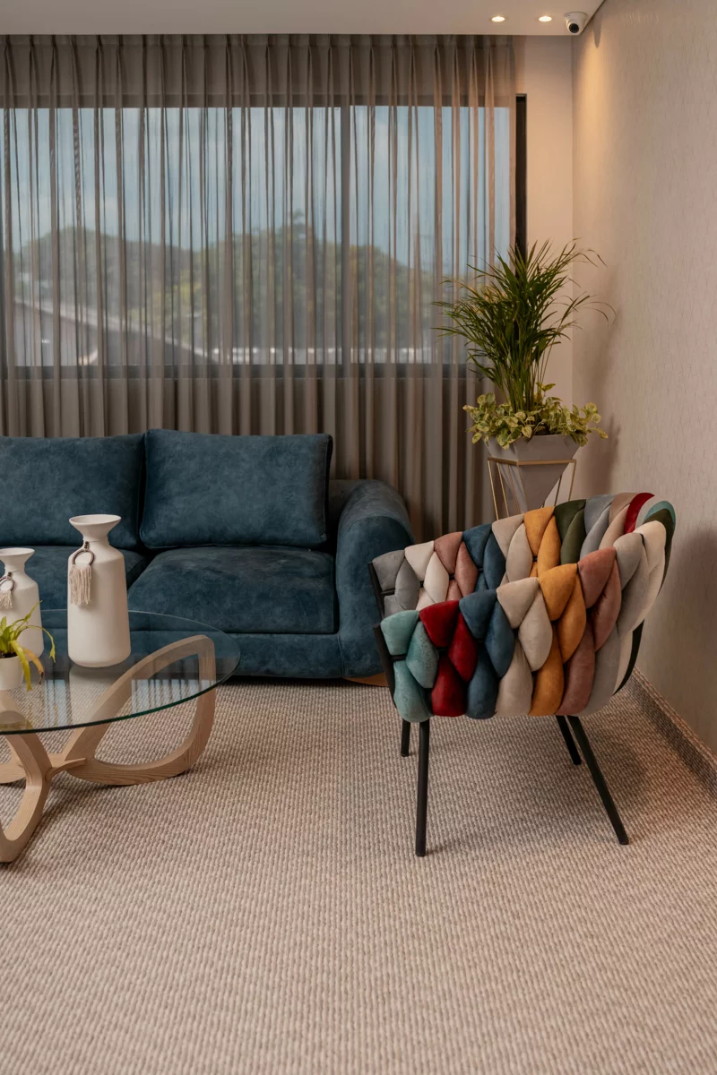 Sala con sofá azul, silla de colores y ventanal